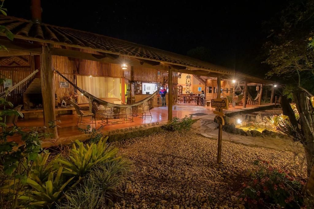 Casa-sede e recepção iluminadas à noite, com jardim de pedras